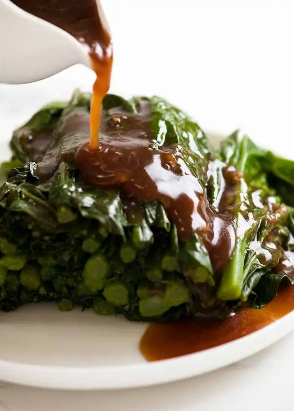 Pouring Garlic Ginger Oyster Sauce over steamed Chinese Broccoli