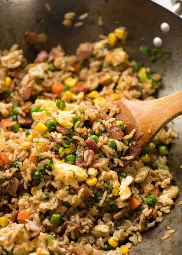 Close up of Egg Fried Rice in a wok with a wooden spoon, fresh off the stove