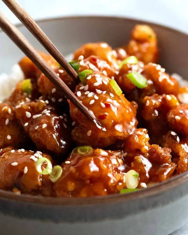 Close up of chopsticks picking up a piece of General Tso